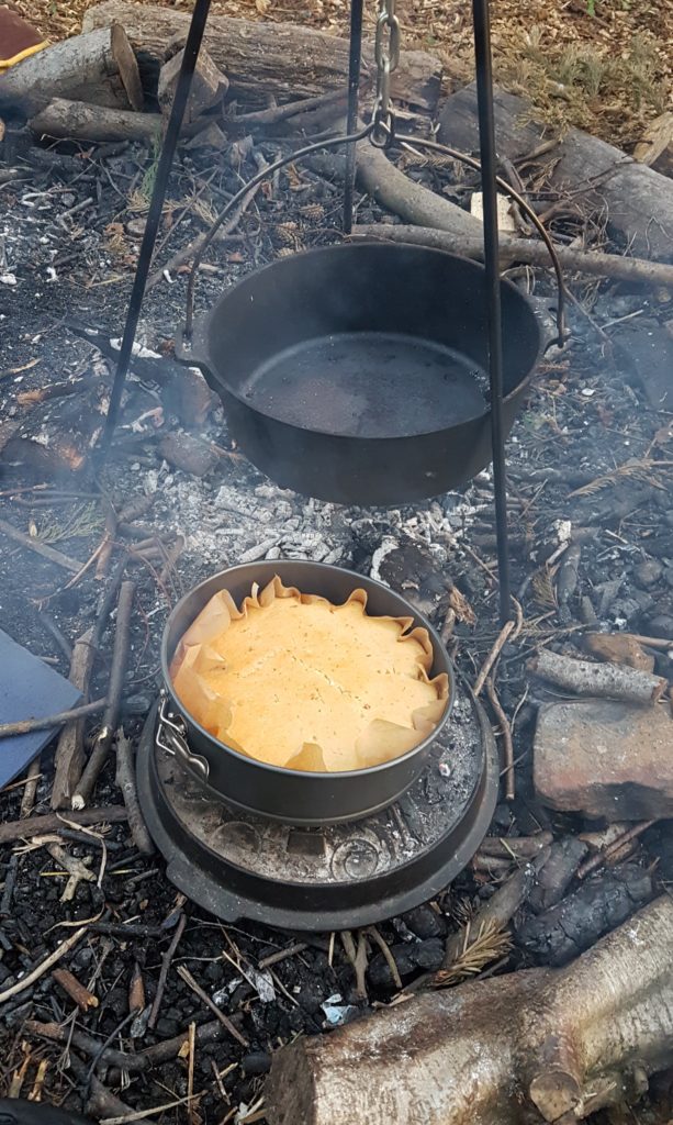 A dutch oven suspended over a fire.